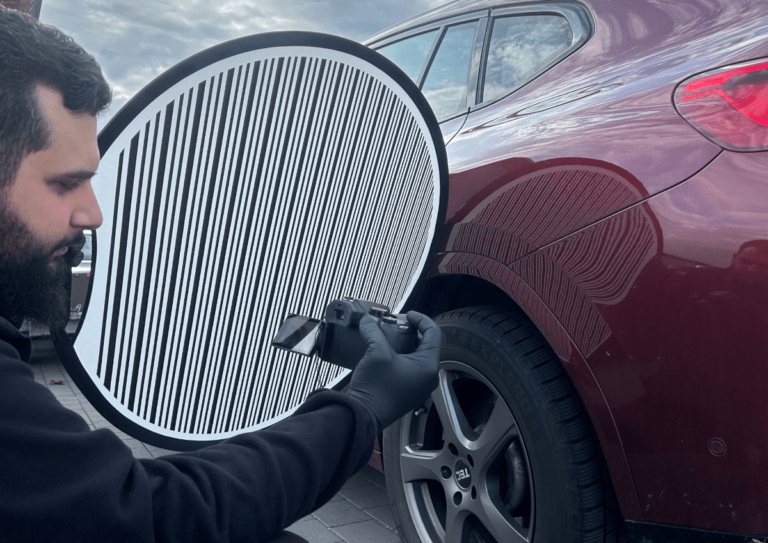 Ein Kfz-Gutachter verwendet einen Dellenschirm, um Dellen und Beschädigungen an einem Fahrzeug präzise zu analysieren. Ideal für eine exakte Schadensbewertung und kosteneffiziente Reparaturen.